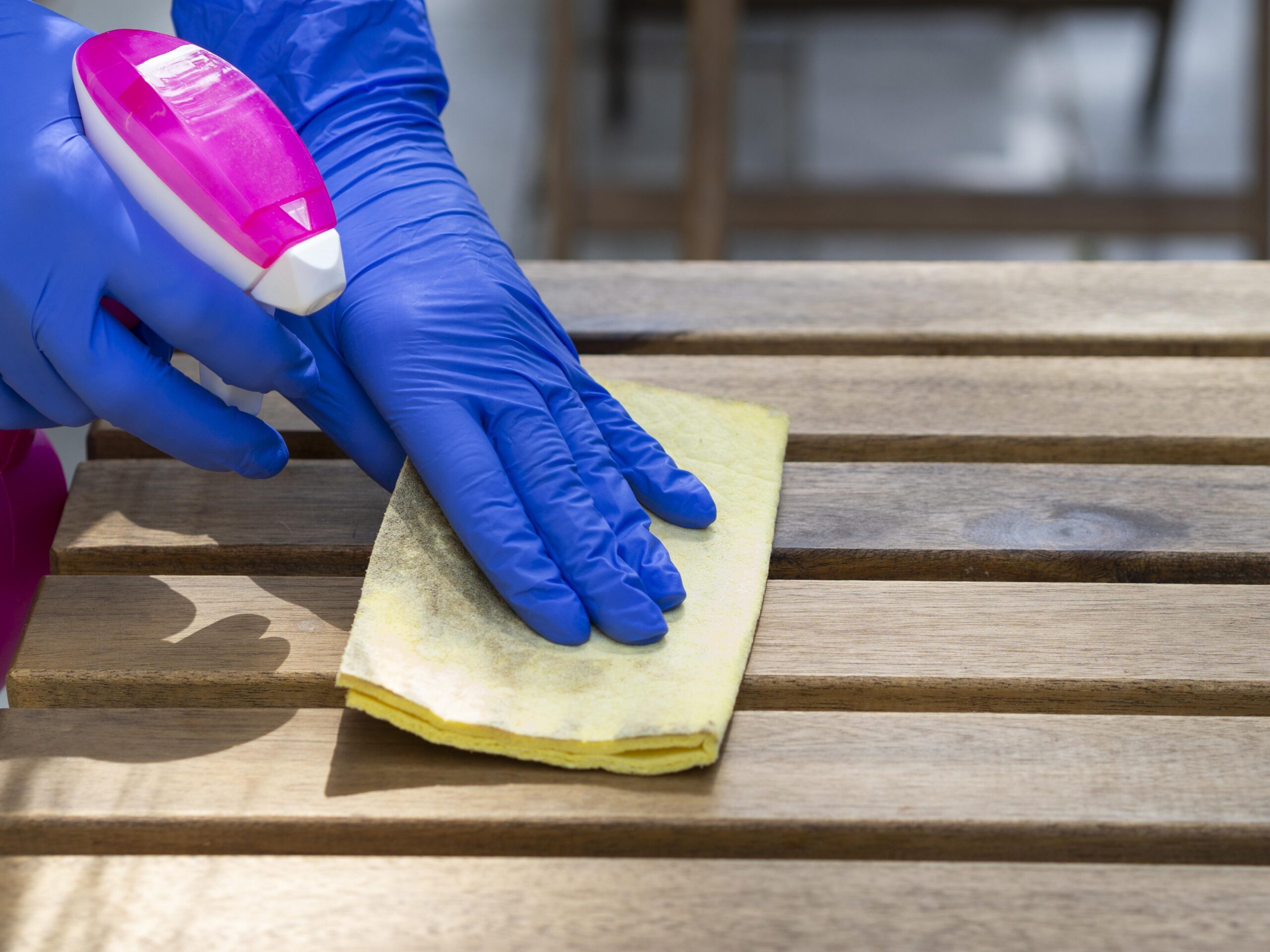 person-disinfecting-wooden-surface