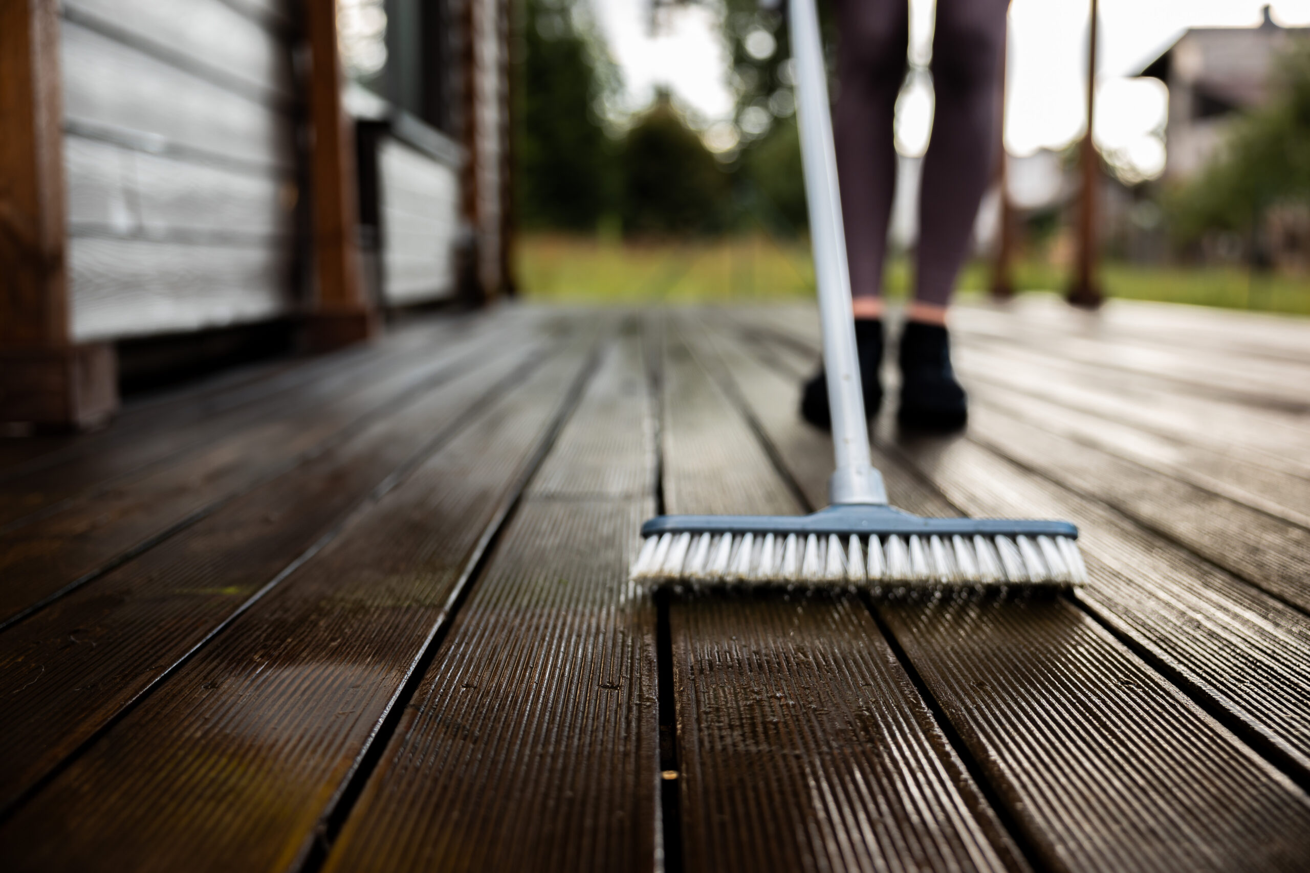 Woman washes a wooden terrace before painting it in her modern p